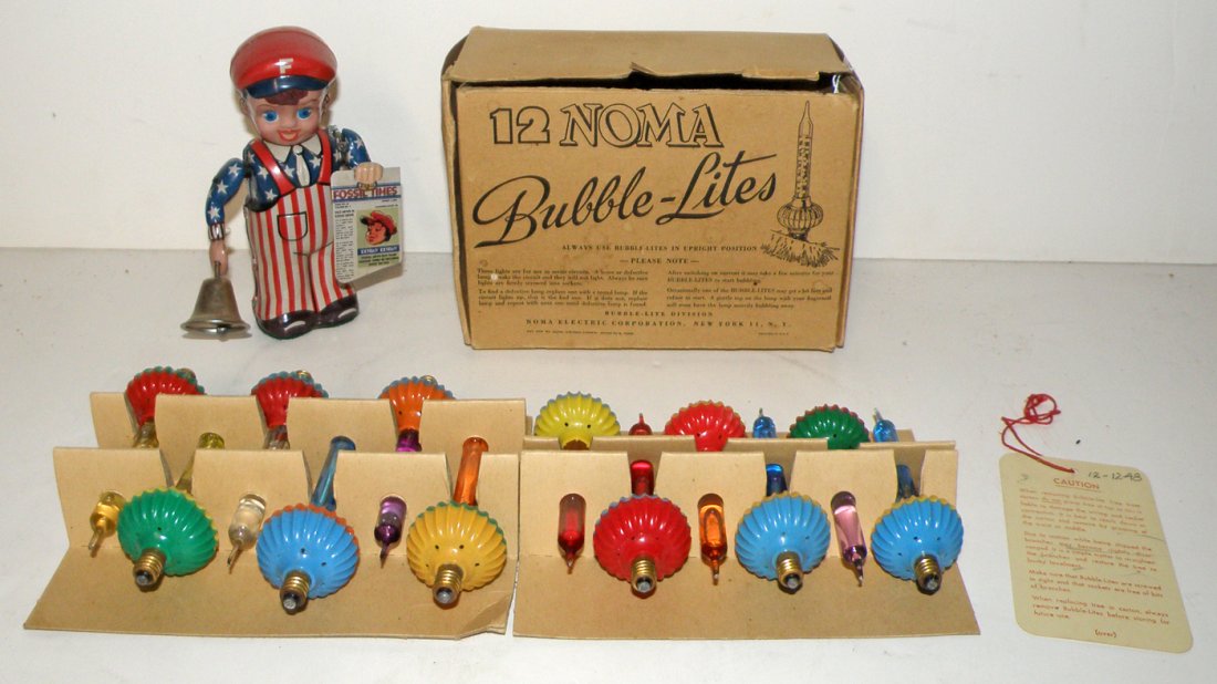 A BOX OF ORIGINAL NOMA BUBBLE LIGHTS AND A WINDUP TOY: Bubble lights retain original tag and appear unused. Tin windup news boy from Fossil Watches. Noma light box lid detached size varies