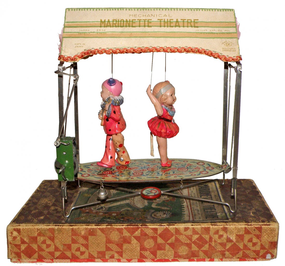 PRE-WAR BOXED JAPANESE MARIONETTE THEATRE: Tin and celluloid toy works fine and retains original canopy. Canopy has minor damage. Original box has some discoloration and small repair to label. Made by Kuramochi. 10" x 11 1/4"