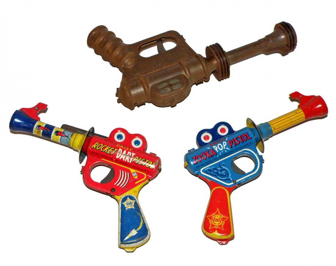 THREE TIN SPACE GUNS BY DAISY: Buck Rogers Disintegrator, Zooka-Pop pistol, and a Rocket Dart pistol which shows more wear. All still function. Largest, 9 1/2" Long