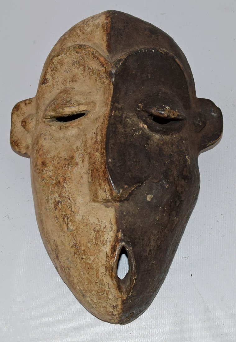 PENDE SHRINE MASK: Carved wood mask with deformed facial features as made. These type of masks were called Mbagu. Retain original bicolor pigmentation. 16 1/2'' tall