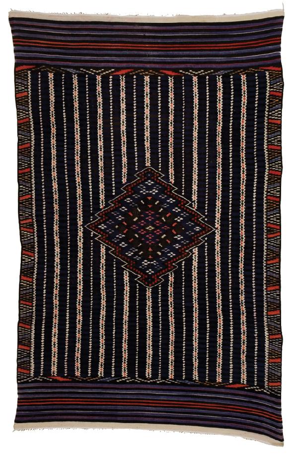 Mexican Transitional Saltillo: 76 x 48" red, blue, purple, white and tan with a classic serrated diamond center and vertical connected diamond stripes with blue and black horizontal bars between them. Good condition shows some wear