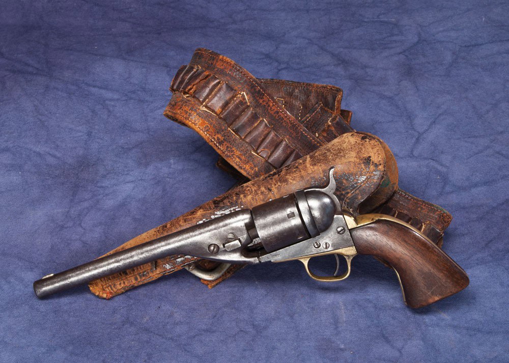 1861 Navy Revolver and Rig: The grips on this well worn gun have Lincoln County history. The early and worn belt and slim jim holster match up very well with the Navy. The bottom of the stocks are ranch carved with Lincoln NM. I