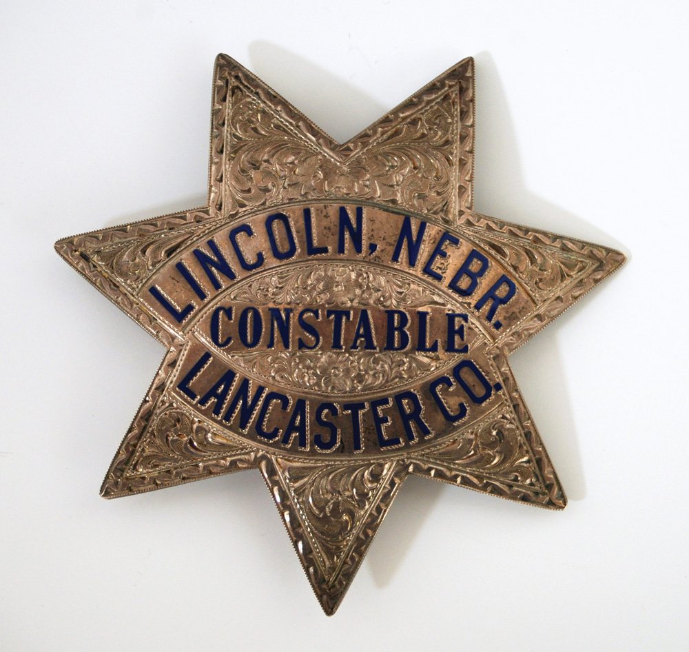 Lincoln, Nebr. – Lancaster Co. – Constable Badge: High finish sterling silver and heavily engraved 6-point large badge with bright blue enamel. A high domed design and 3 1/4” across the points. Marked on reverse “Ed Jones & Co. Oakland, Cal. Ster