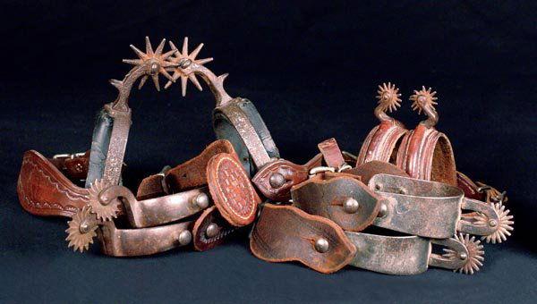Four (4) Pair of Early Cowboy Spurs: All attributed to August Buermann: (a) Star & Pat'd marked #1287, with original attached leathers, rusty with leathers receding; (b) the classic double button OK spurs, unmarked; (c) unmarked Pat #32