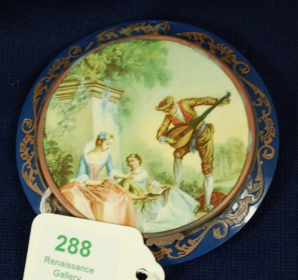 FRENCH ART DECO COMPACT: 3.5" IN DIAMETER, APPEARS TO BE CELLULOID, BLUE WITH GOLD TRIM, TROUBADOR SCENE ON THE LID, BUYER ARRANGES SHIPPING, WE CAN RECOMMEND LOCAL SHIPPERS.