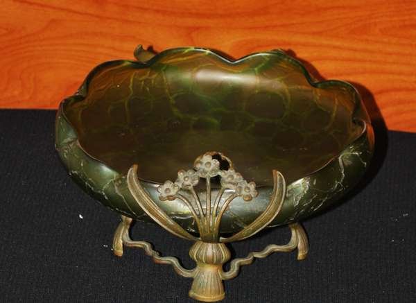 ARTS & CRAFTS GLASS BOWL: RAISED GREEN GLASS BOWL WITH METALWARE STEM & FLOWER BASE, METALWARE FINIAL IN MIDDLE OF BOWL, DAMAGE TO ONE SIDE OF BASE, ATTRIBUTED TO LOETZ GLASS, SITS 4.5" HIGH, BUYER ARRANGES SHIPPING, WE CAN RE