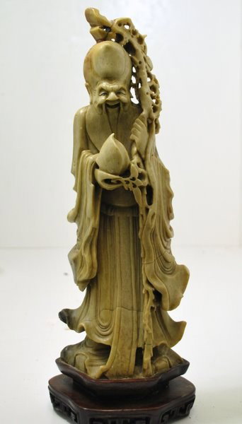 LARGE SOAPSTONE FIGURE OF A HOLYMAN ON A WOOD BASE: LARGE SOAPSTONE FIGURE OF A ORIENTAL HOLYMAN ( PRIEST ) ON A WOOD BASE, 16 " TALL.
