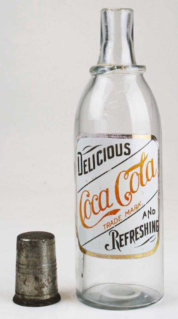 Early Coca-Cola syrup bottle: Rare Coca Cola bottle with enamel label. Age appropriate wear to bottle and label. Oxidation to cap. 11" high.