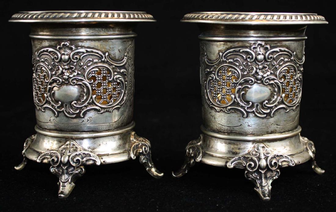 pair of German coin silver wine coasters: pair of early 20th c. German 800 coin silver bottle holders or wine coasters, having gadrooned rim over rococo repousse motifs and reticulated latticework cartouches, on sculpted feet with gold wash v