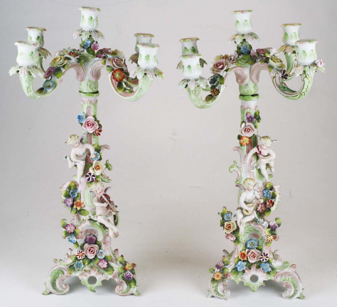 Pair of Dresden two part candelabra: Pair of fine ca. late 19th or early 20th c. Dresden style porcelain two part figural candelabra with pastel toned rococo scrolls surrounding handpainted floral cartouches, accented by modeled flowers,