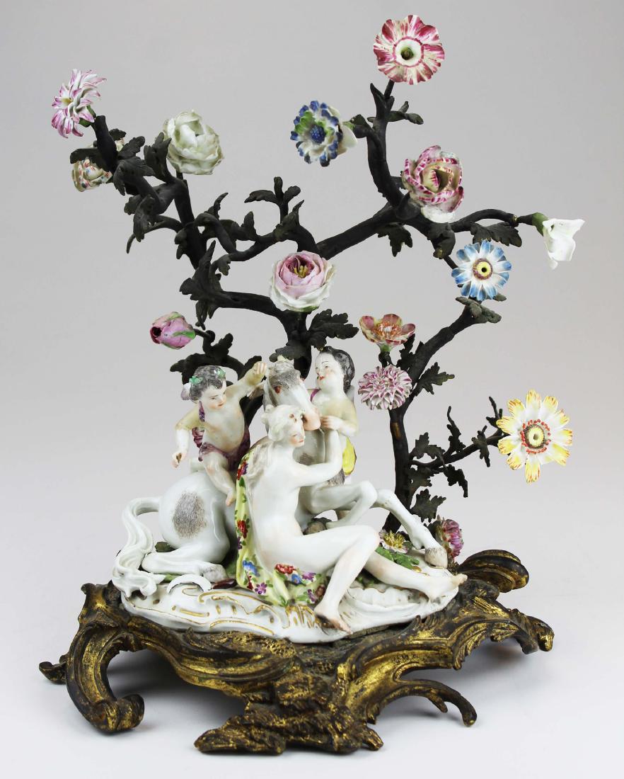 19th c. Meissen porcelain and bronze figurine: 19th c. Meissen type porcelain figural group consisting of nude woman and two cherubs surrounding reclining horse, set on gilt bronze base supporting bronze trees bearing modeled porcelain flowers -fi