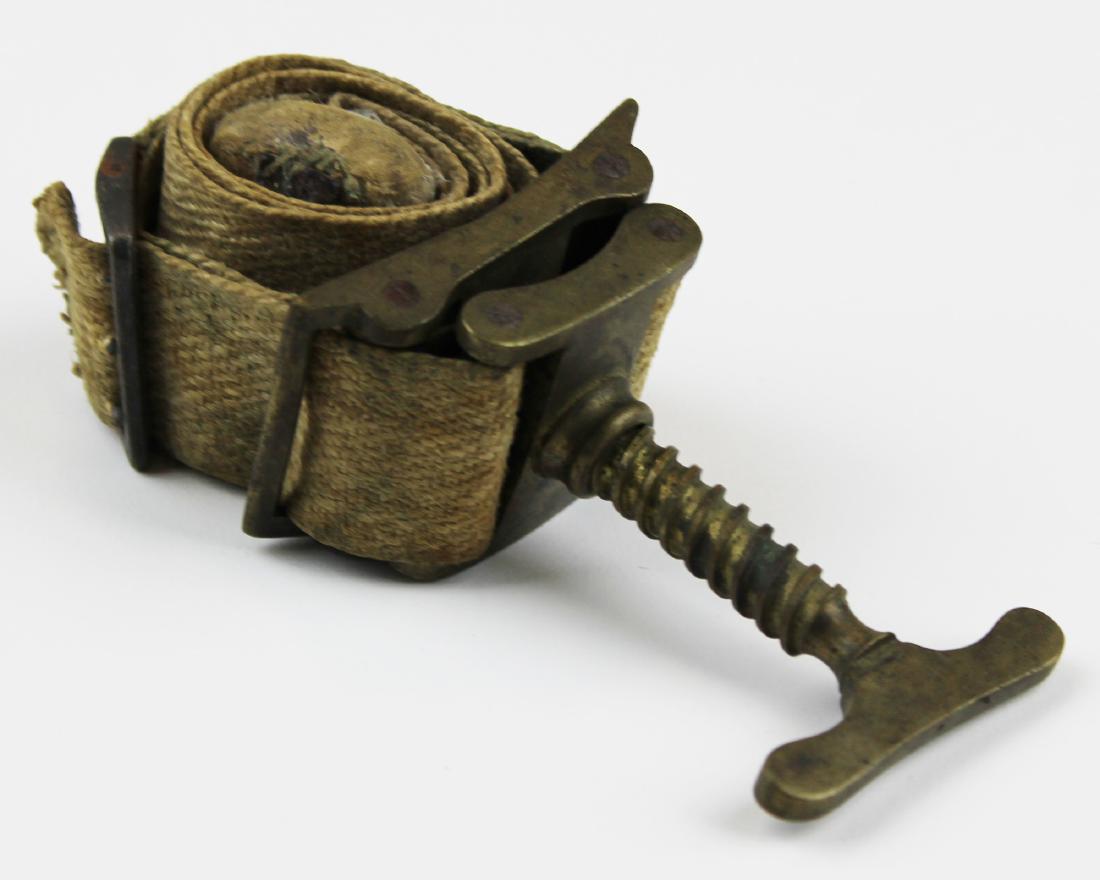 19th c Signed Evans London brass & canvas tourniquet: 19th c signed Evans London brass & canvas clamp tourniquet. 5" h. Screw brass clamp with brass lower panel and canvas straps. 1 1/2" wide.