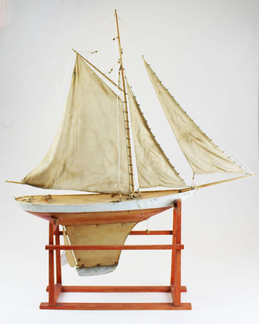 late 19th c. painted tin pond sail boat: late 19th c. painted tin pond sail boat "Avis" in old orange paint on matching display stand 33" x 28" overall