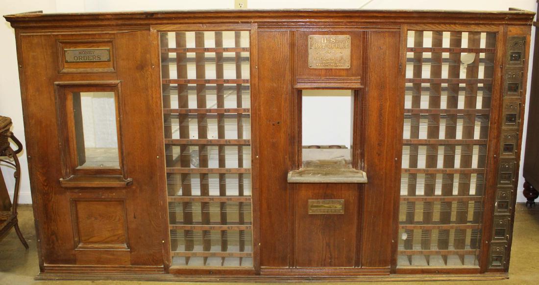 oak post office mail boxes from East Calais, VT: oak framed bank of mail boxes originally from the East Calais, VT, P.O. with metal lettered "East Calais Post Office" sign (repainted), made by Sadler Co. Baltimore, MD featuring 85 glass front mail p