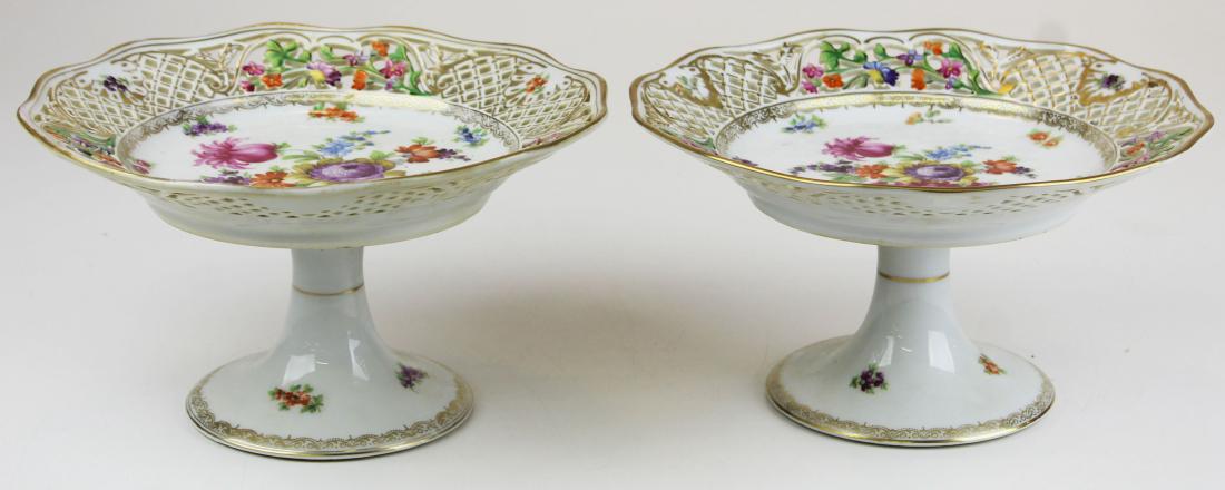 pair of Schumann Dresden style porcelain compotes: pair of Schumann Bavarian porcelain Dresden style compotes with reticulated lattice style borders and floral decoration one with minor rim nick on base 5.25" x 9.25"