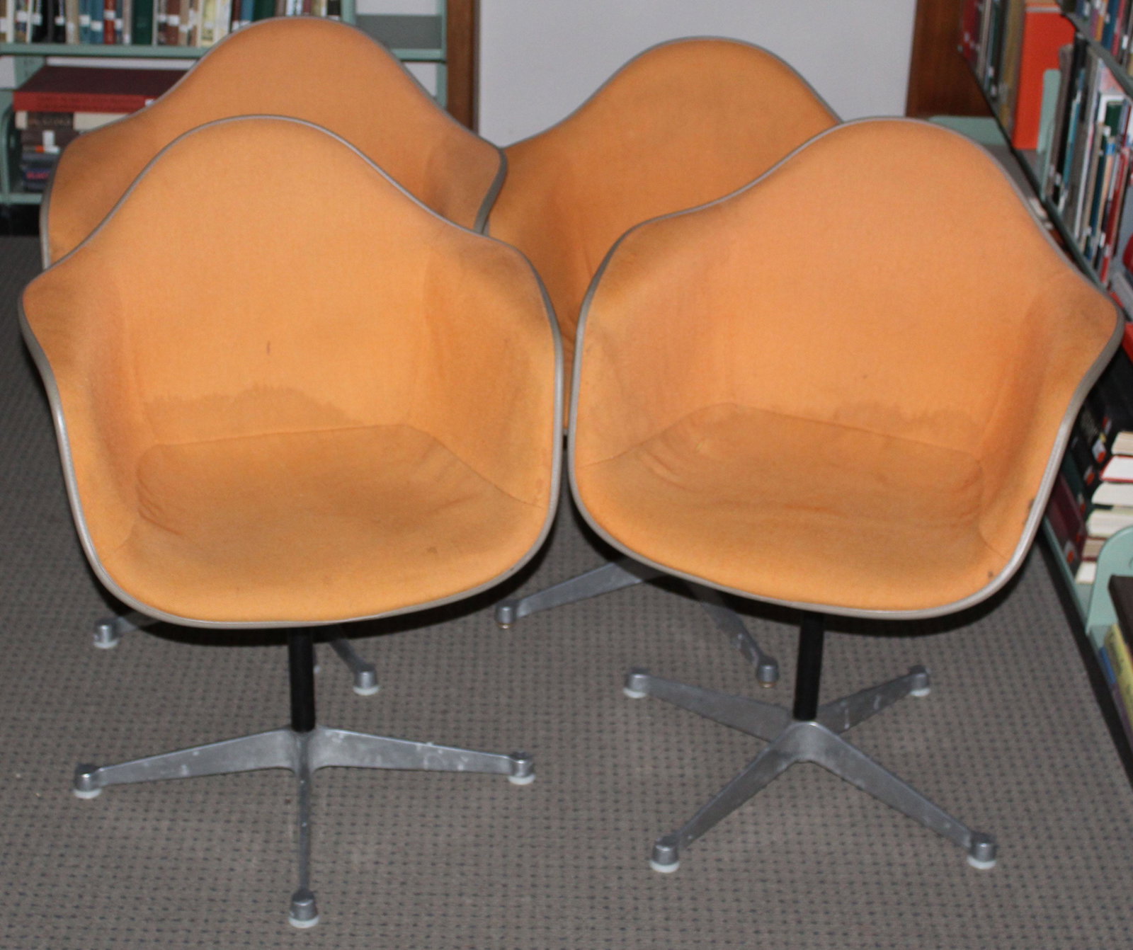 Four Herman Miller Chairs: Four Charles and Ray Eames designed Herman Miller "La Fonda" mid- century industrial shell chairs in Orange upholstery most marked FEB 1970 some with GMC LIB etched on underside of shell