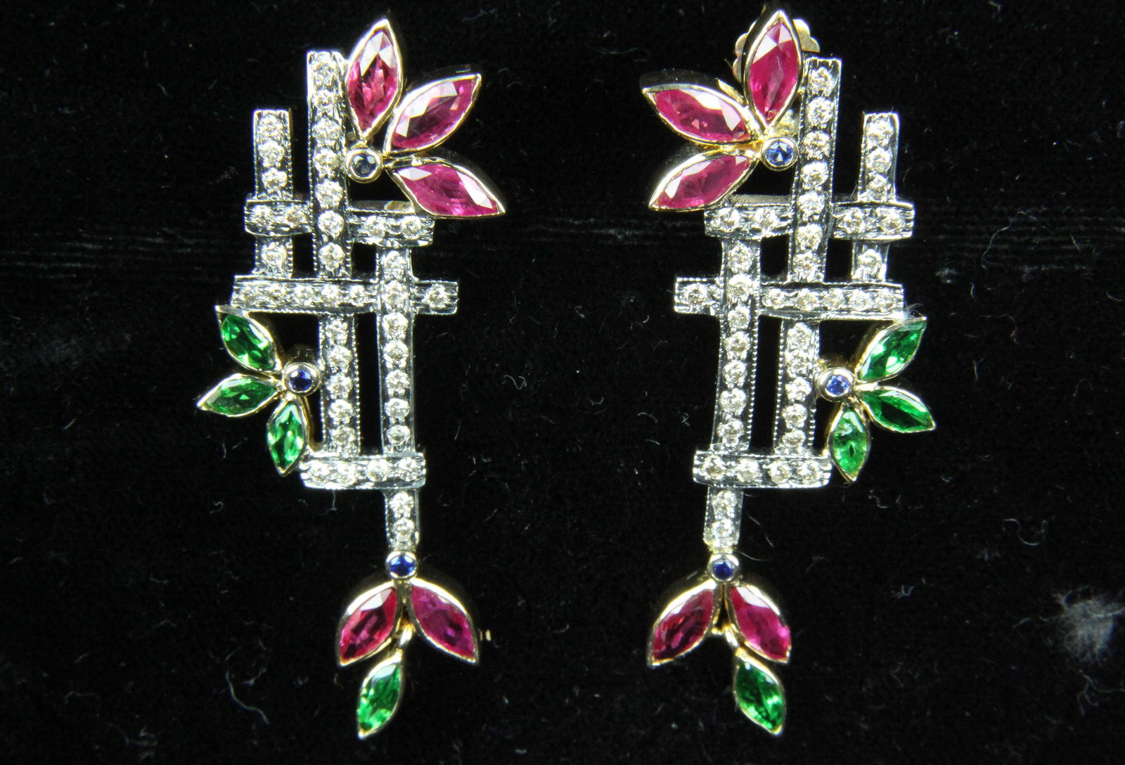 Ruby, diamond, sapphire, green tourmaline earrings: A ornate pair of earrings set with green garnet, diamonds, rubies, and sapphires in a holiday floral motif. Set in sterling and yellow gold. 2" long.