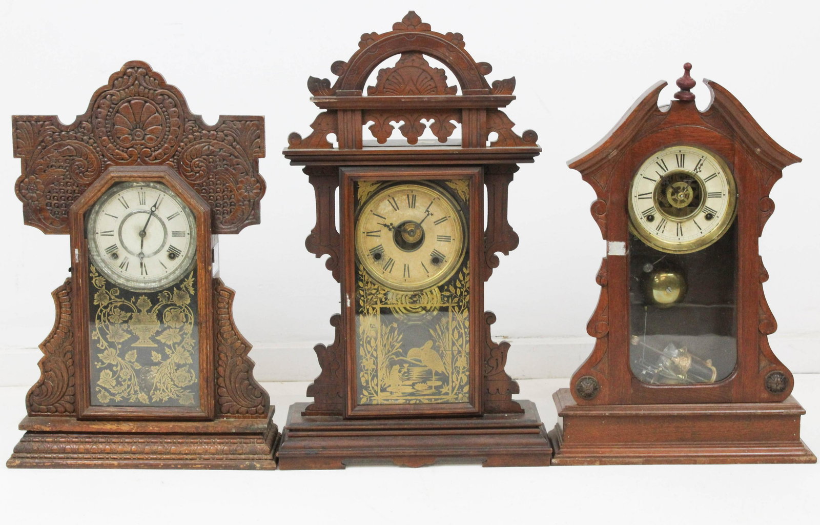 Three Victorian Gingerbread Clocks: Three Victorian Gingerbread oak, black walnut shelf clocks, sold with mahogany OG clock & a steeple clock for parts, hts from 19" to 26"