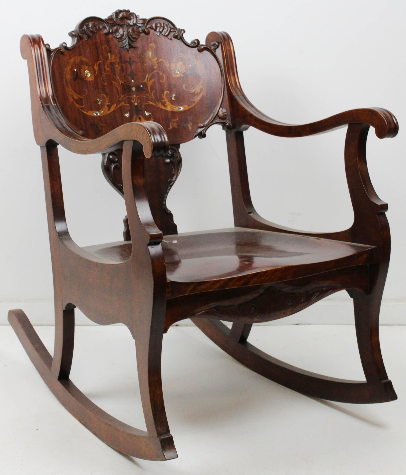 ca. 1910 Inlaid Mahogany Parlor Rocker: ca. 1910 Mahogany parlor rocker with marquetry inlaid back having mother of pearl accents and floral carved crest 33" x 31" x 21"