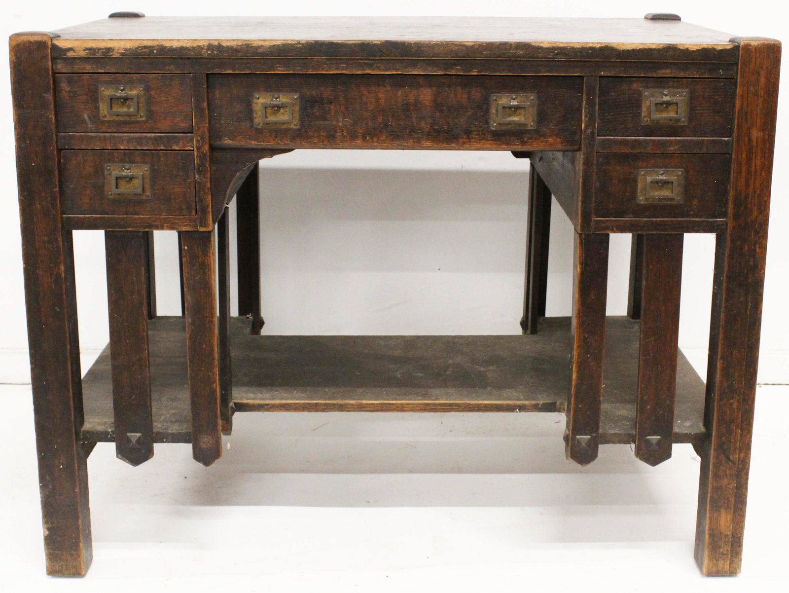 Mission Oak Kneehole Desk Library Table: ca. 1910 Mission style oak kneehole desk library table with 3 drawers and lower shelf, retaining original brass hardware, in dark old finish 29.5" x 38" x 24"