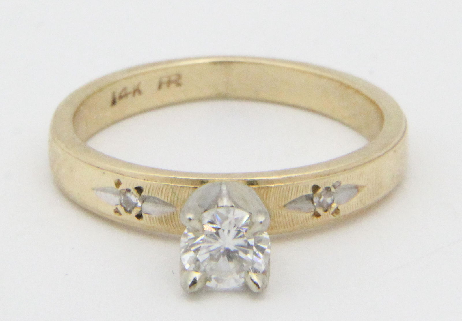 Diamond engagement ring: A diamond and 14k yellow gold diamond engagement ring having a round cut 1/4 ct solitaire set with 2 .01 ct diamonds each side in band. Ring size 5.