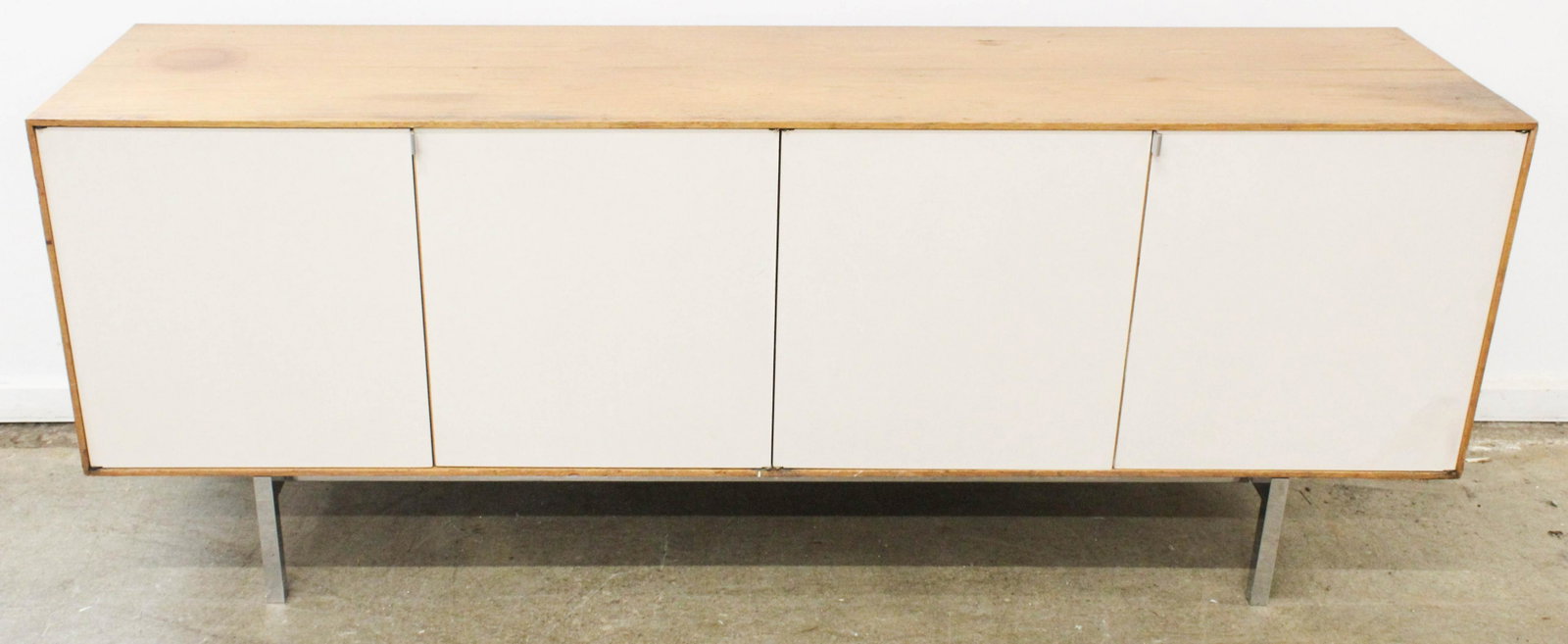 Florence Knoll credenza: A attributed Florence Knoll credenza or long cupboard. Walnut exterior, with 4 white laminate doors, maple interior, on chrome steel legs and frame. 6' long.
