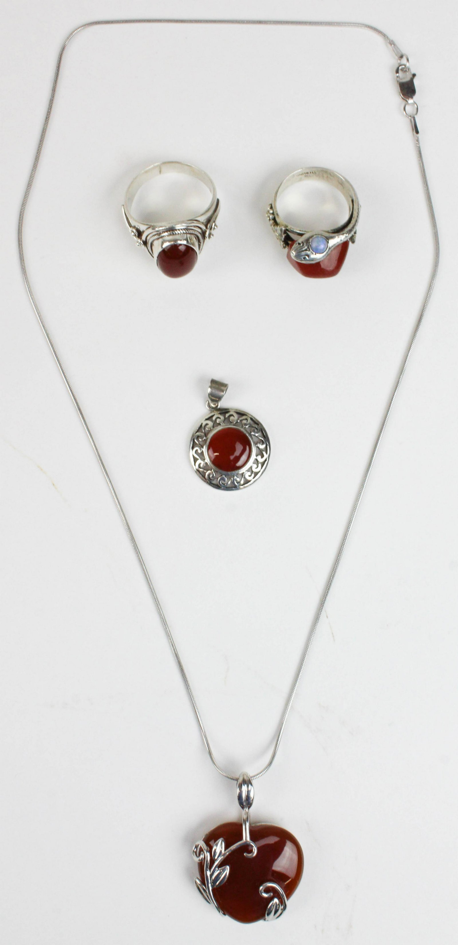 4 pieces of sterling and Carnelian jewelry: 4 pieces of sterling and Carnelian jewelry. Including a snake ring with round opal eye and Carnelian stone. Oval bezel set Carnelian ring in sterling size 9. A Carnelian heart and sterling pendant. St