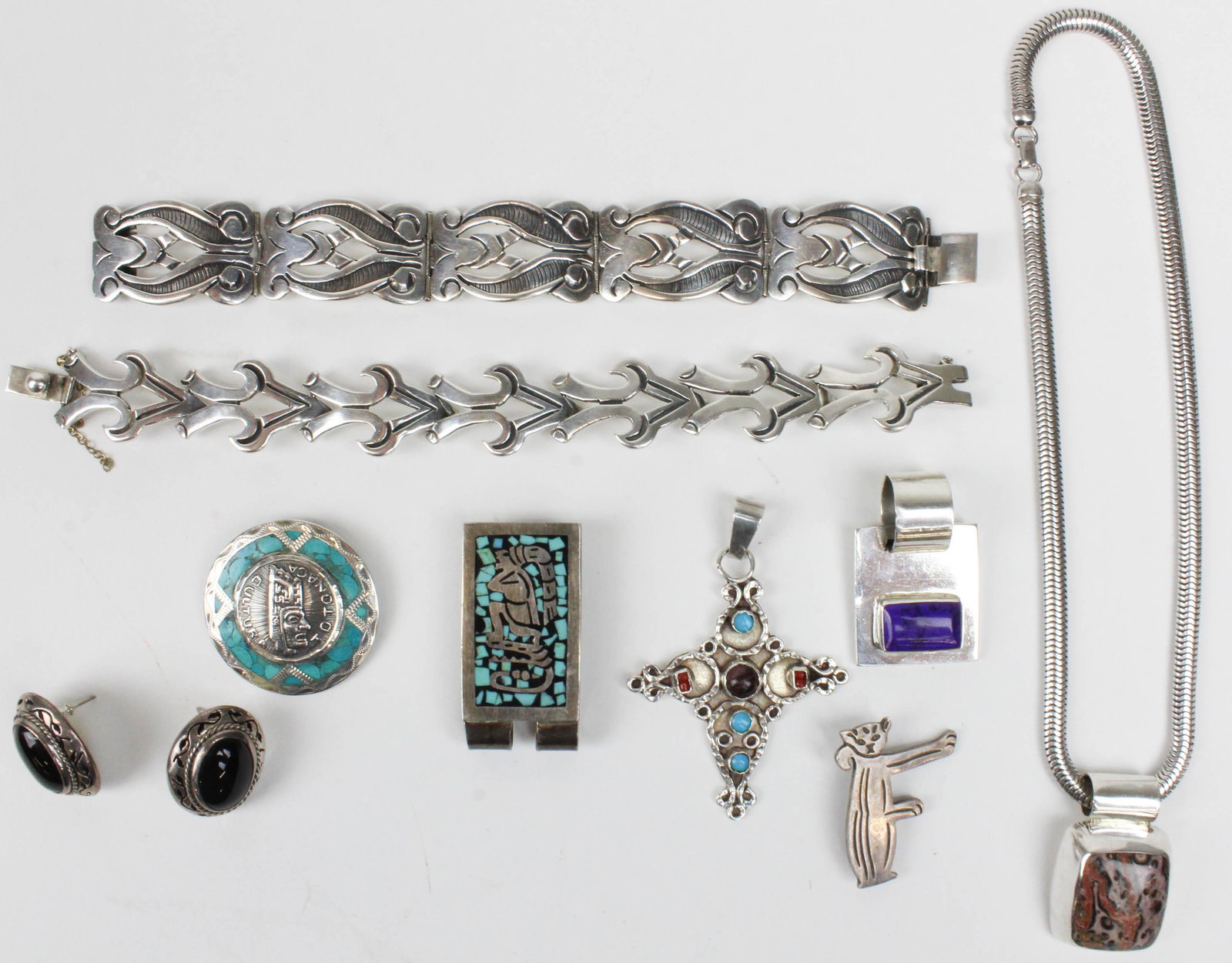 A group of Mexican sterling jewelry: A group of Mexico sterling silver jewelry including two bracelets, pair of onyx earrings, jeweled cross, money clip, pendant, and two brooches.