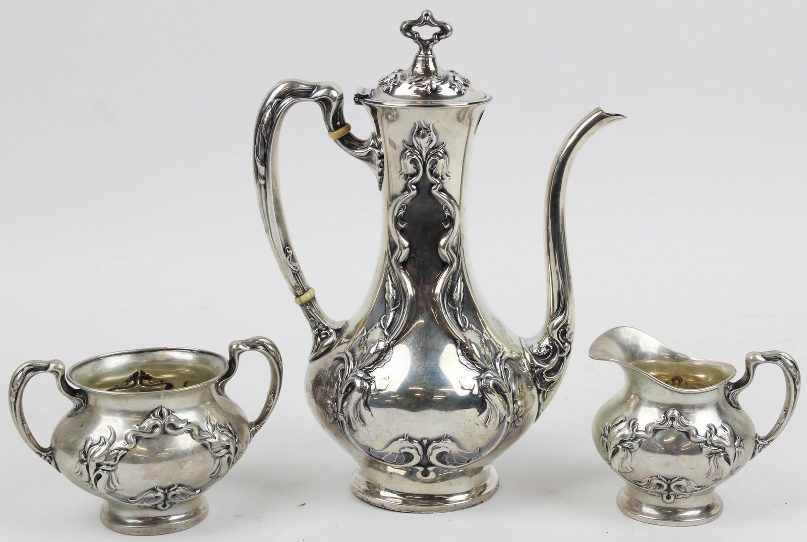 Wallace Art Nouveau Sterling 3 pc. Demitasse set: Wallace sterling silver 3 pc. demitasse set consisting of coffee pot, open sugar bowl, and creamer, having Art Nouveau repousse iris decoration 9.75" x 7",3.5" x 5" approx. 19 troy oz. estimated -hand