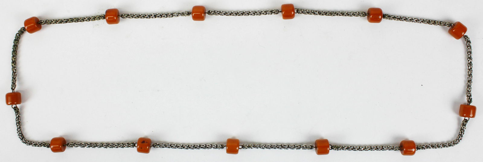 Sterling & Bakelite barrel necklace: A sterling a Bakelite necklace having 13 11mm x 14mm Carmel colored Bakelite barrels set into a complex sterling chain. 38" long.