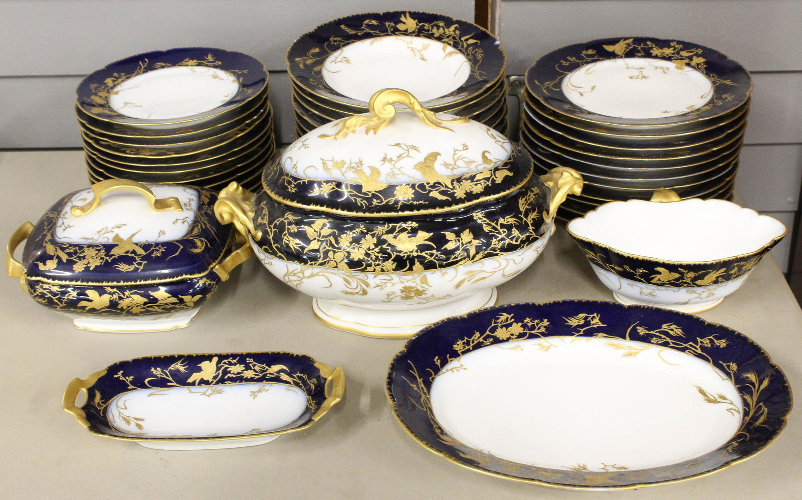 38 pcs. Jean Pouyat Limoges Cobalt Gilt Porcelain: 38 pcs. Late 19th c. Jean Pouyat Limoges porcelain dinnerware with cobalt blue banded border, and raised gilt enamel accents featuring birds and foliage, consisting of covered tureen, oval serving pla