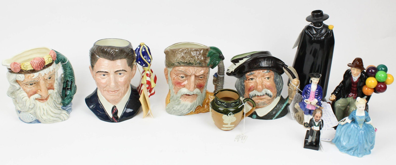 Royal Doulton Toby Jugs and Figurines: Collection of Royal Doulton porcelain items including Ronald Reagan, Neptune, Robinson Crusoe, Sancho Ponca character toby jugs, "A Child from Williamsburg" and "A Boy from Williamsburg" Colonial Will