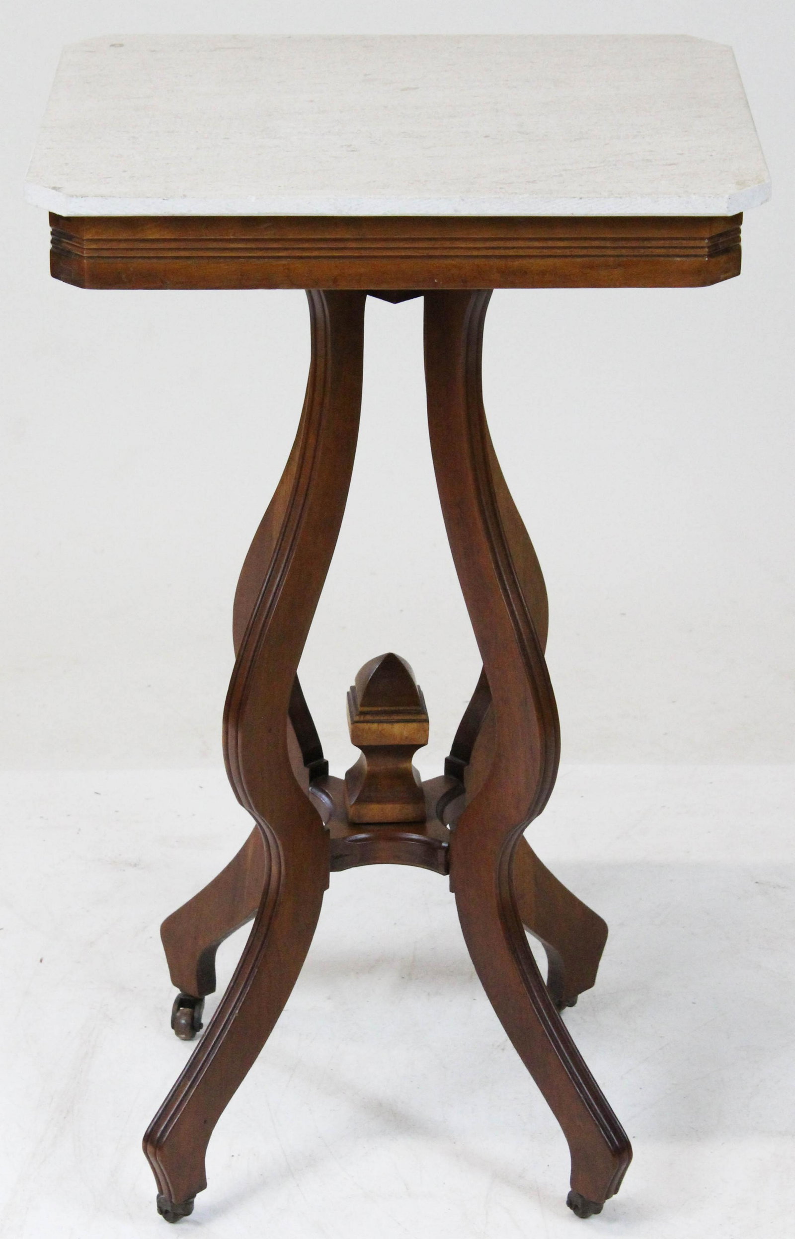Victorian Marble Top Side Table: Victorian walnut side table with a tan stone top. Castors, 4 saber legs, center pediment, 18" x 14" x 30" h.