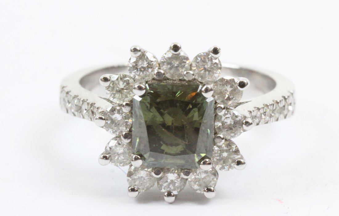 1.9 ct Solitaire Green Diamond Ring: A 14k white gold ring set with a rectangular or radiant cut 1.9 carat treated green diamond measuring 7 mm x 6.2 mm x 4.5 mm. With a 12 round cut diamond surround each approx. .04 cts and 6 small diam