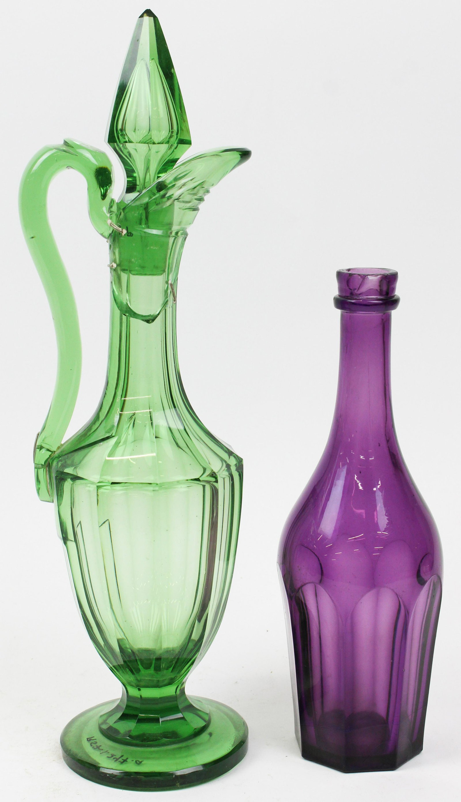Emerald Claret Decanter and Amethyst Bottle: Rare 19th c. emerald green paneled cut glass footed claret wine decanter with applied cut handle (neck damaged, old professional staple repairs), accompanied by a scarce amethyst purple mold blown pan