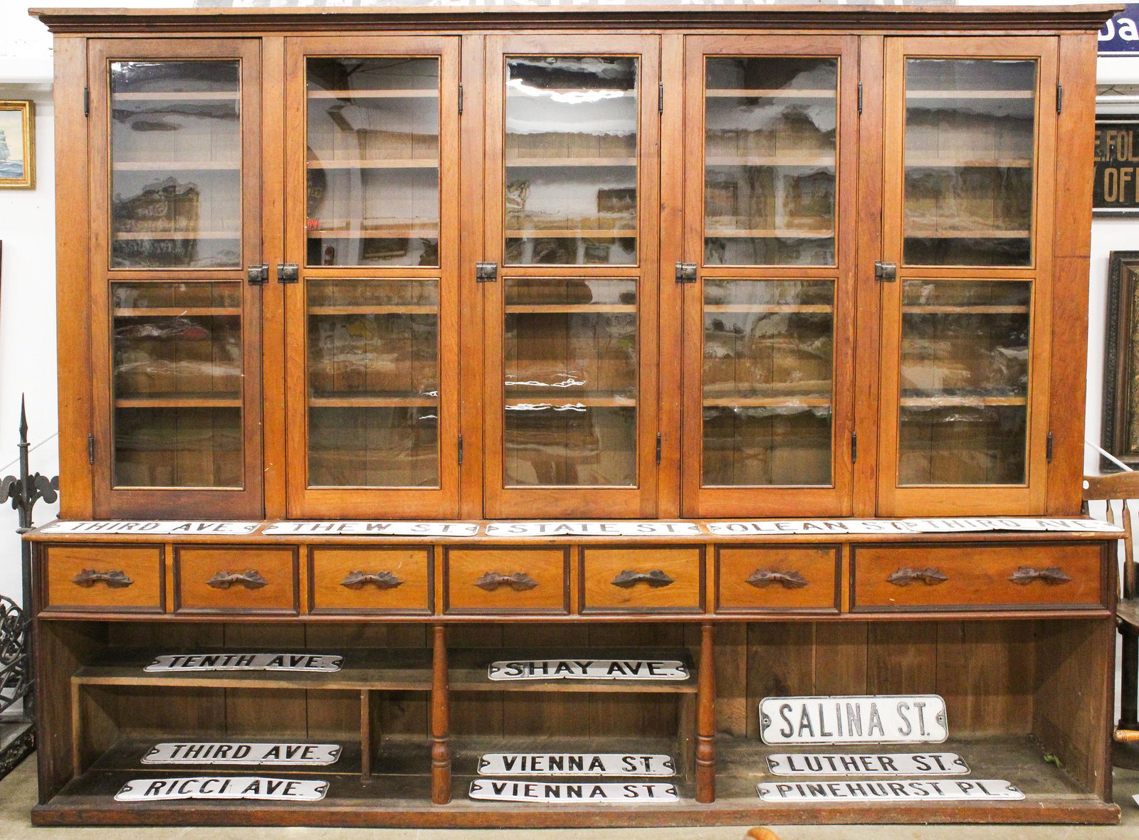 Large 10 Foot Wide 2 Part Country Store Cupboard: Large late 19th c. butternut 2-part stepback country store display cupboard with glass 4 door upper cabinet section over base having 6 dovetailed drawers with carved black walnut leaf form pulls, supp