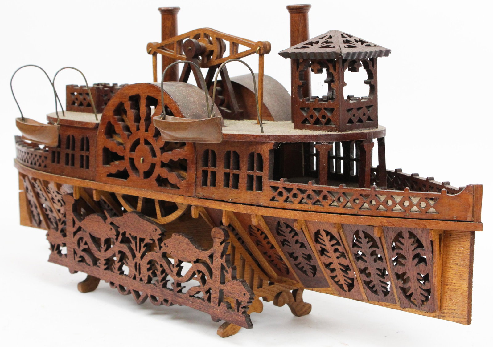 ca. 1920 Folk Art Mahogany and Walnut Steamboat: ca. 1920 folk art mahogany and walnut jig saw cut fretwork articulated model steamboat on stand with fish, likely was originally a watch hutch with one paddle wheel open for pocketwatch 12" x 23" x 36