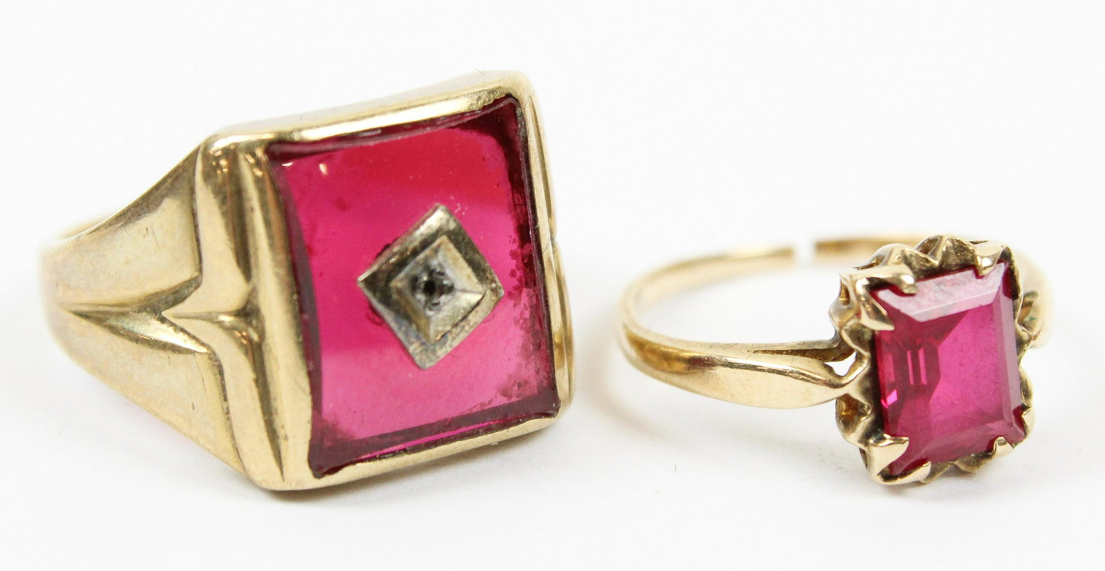 Two Ruby Rings: 10k yellow gold rings. Men's ring with rectangular synthetic panel, center setting point missing stone, ring size 10.5. Woman's 10k yellow gold ring with emerald cut synthetic ruby. Ring size 6.5 - sp