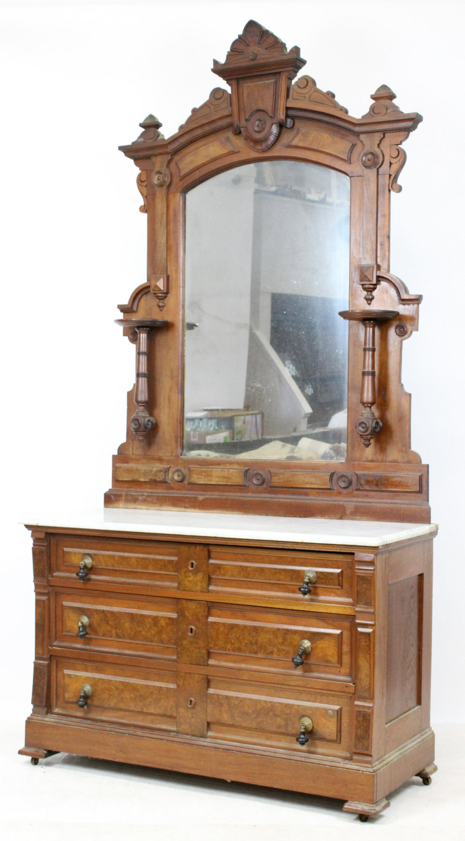 Victorian Renaissance Revival Marble Top Dresser: Victorian Renaissance Revival black walnut marble top dresser having three drawers with applied burl panels and ebonized drop pulls, surmounted by tall carved crest mirror with candle shelves 93" x 47