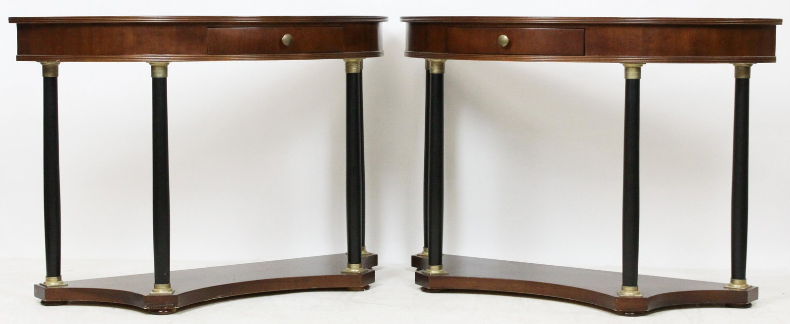 Pair of Italian Neoclassical Demilune Tables: Pair of late 20th c. Italian Neoclassical Biedermeier style mahogany demilune console hall tables having lower shelf supporting ebonized columns with ormolu capitals and single drawers, marked "Made i