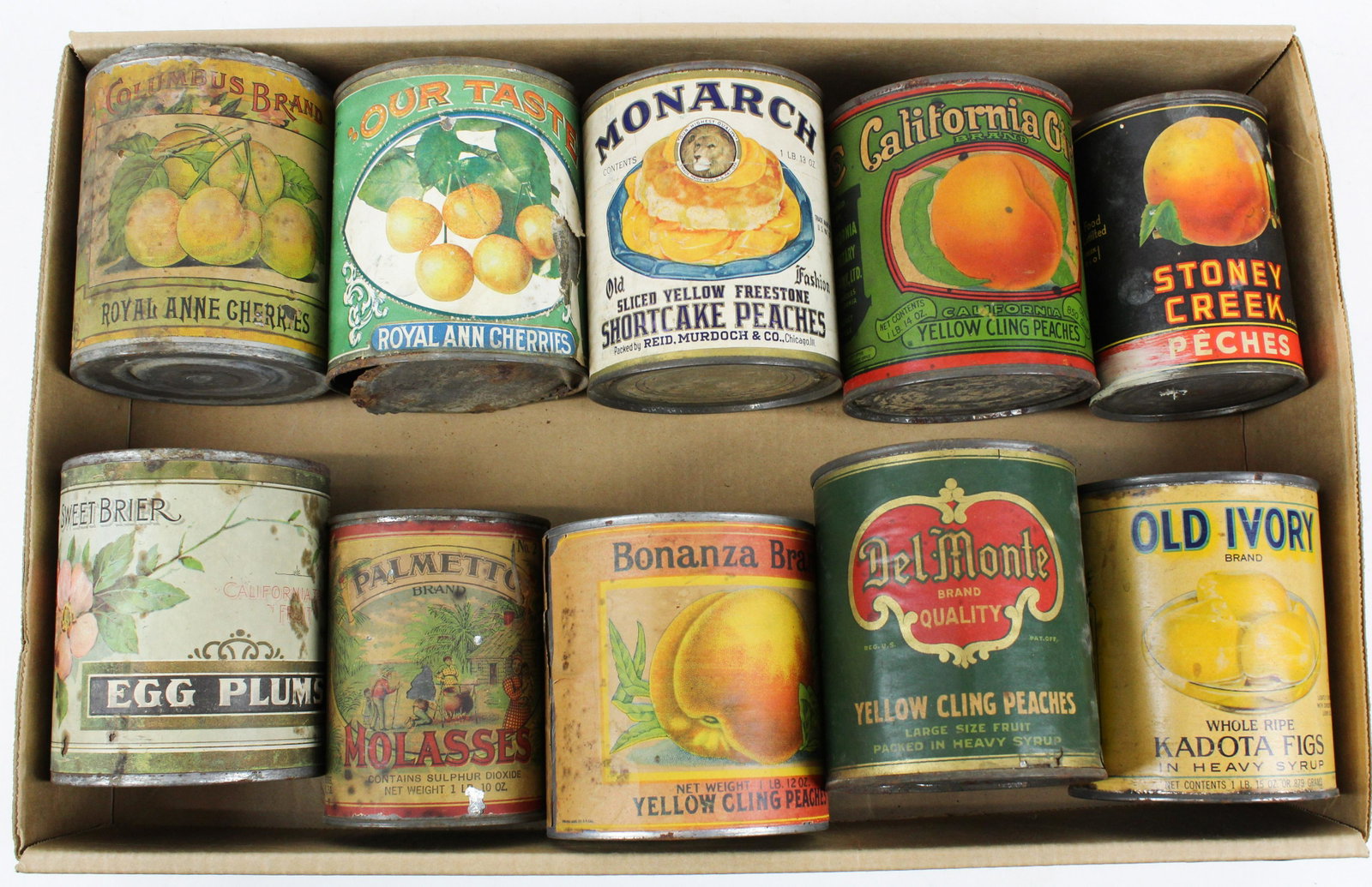 10 Antique Fruit and Molasses Advertising Tin Cans: Collection of 10 ca. 1890-1940 antique fruit and molasses advertising tin cans with colorful graphic paper labels including Monarch shortcake peaches, Palmetto molasses with African American cabin sce