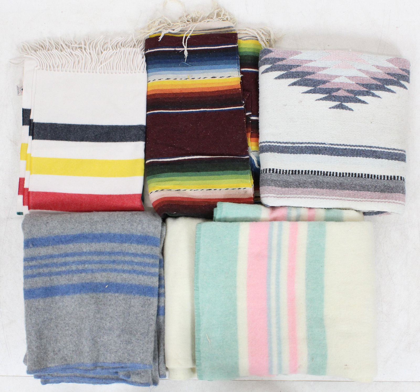 Southwest and Wool Camp Blankets: Lot of vintage blankets including Pendleton Hudson Bay style fringed throw (unused condition), 2 thick wool camp blankets in like new condition, and two Southwestern style colorful woven cotton saddle