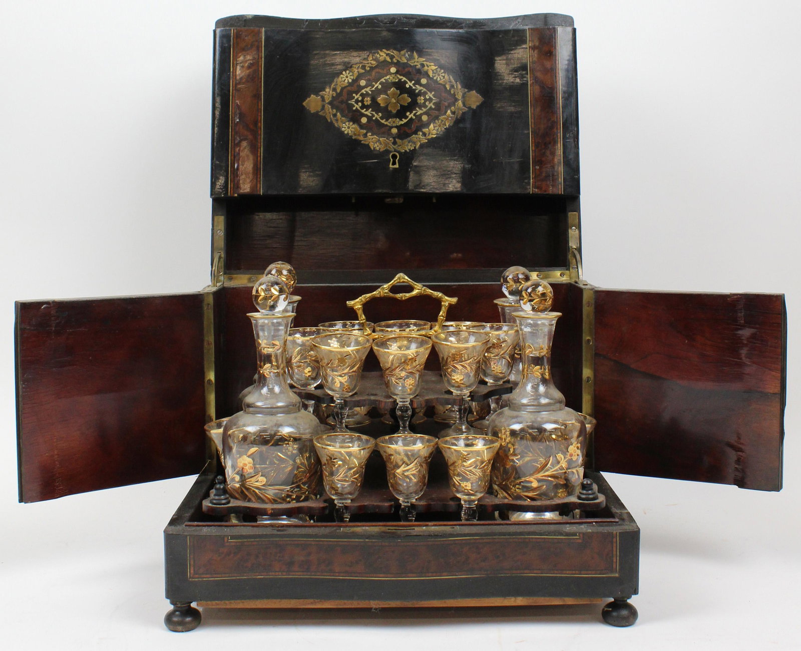 French Boulle Inlaid Tantalus Set: French ebony, burl, and brass inlaid boulle tantalus set, consisting of four decanters with 16 small wines, all good, inlaid case in good condition, 12 1/2" x 10" x 9"