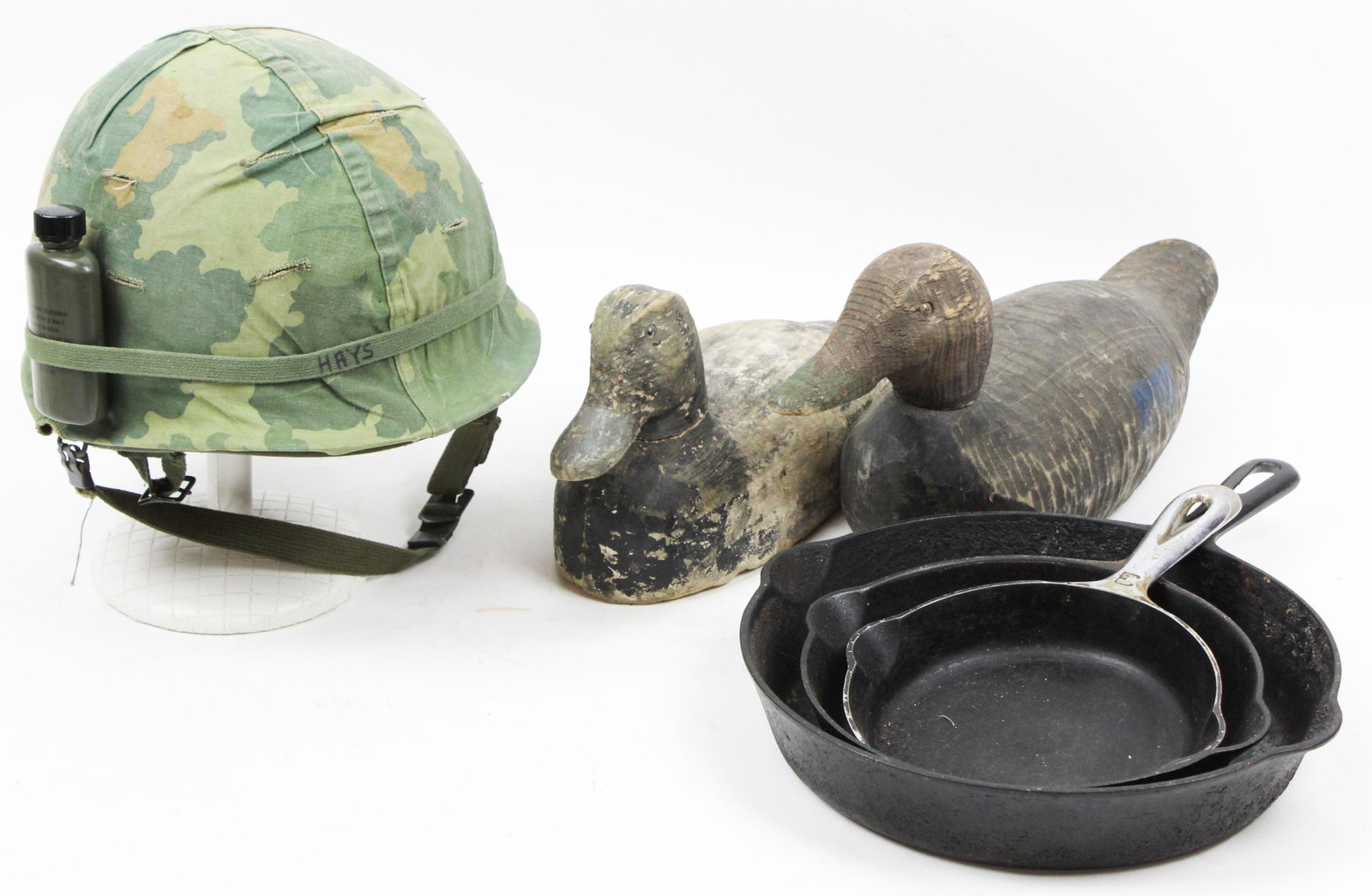US Army Helmet, Griwold Cast Iron, Decoys: US Army Vietnam War combat-used helmet, 3 Griswold cast iron frying pans (one large block letters), two factory duck decoys