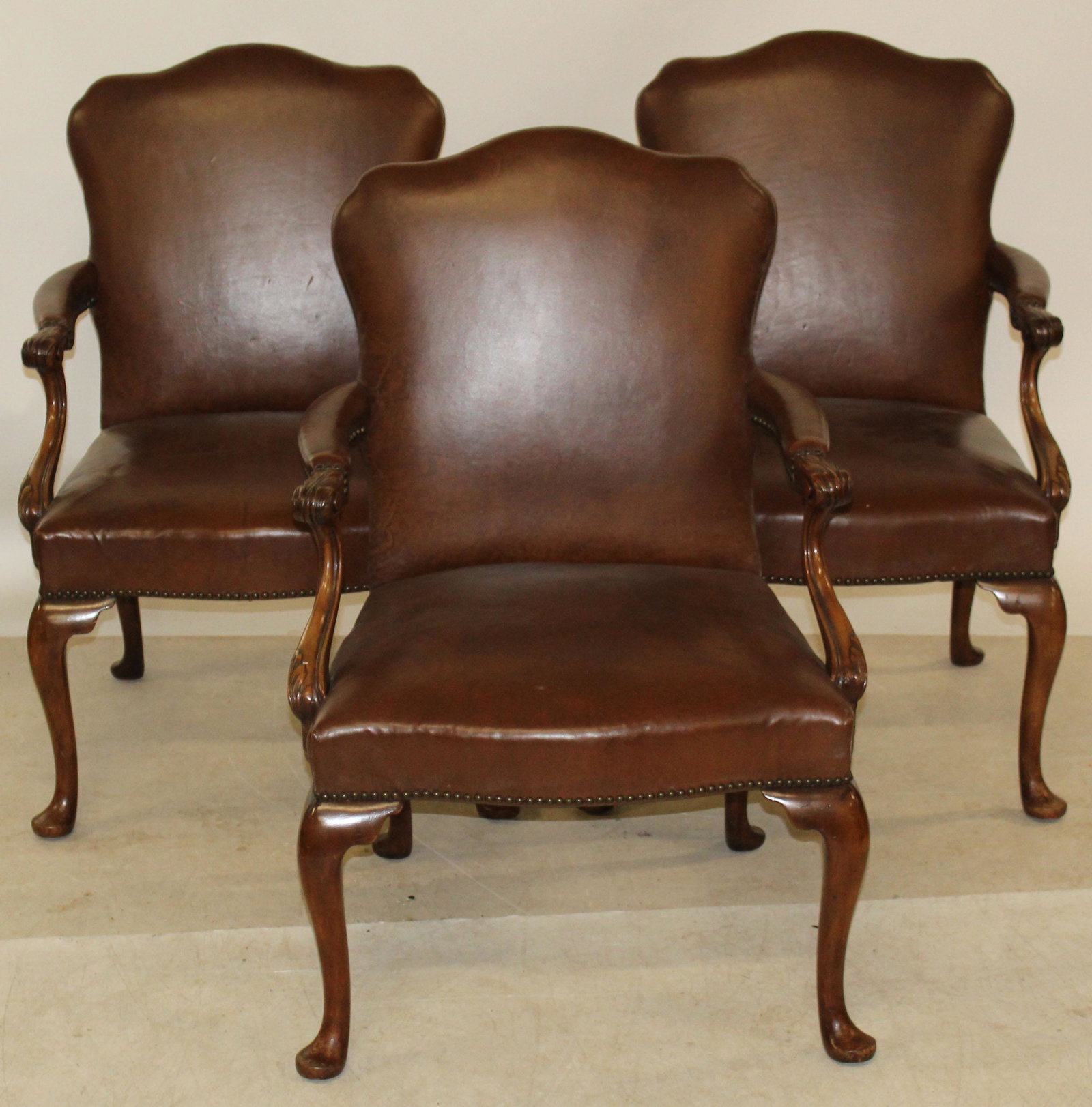 Three Acanthus Carved Armchairs: Three Walnut Acanthus Carved Armchairs from officess of Standard Oil NYC- covered in brown faux leather with brass tack decoration. 23 x 24 x 40" 18" to seat.
