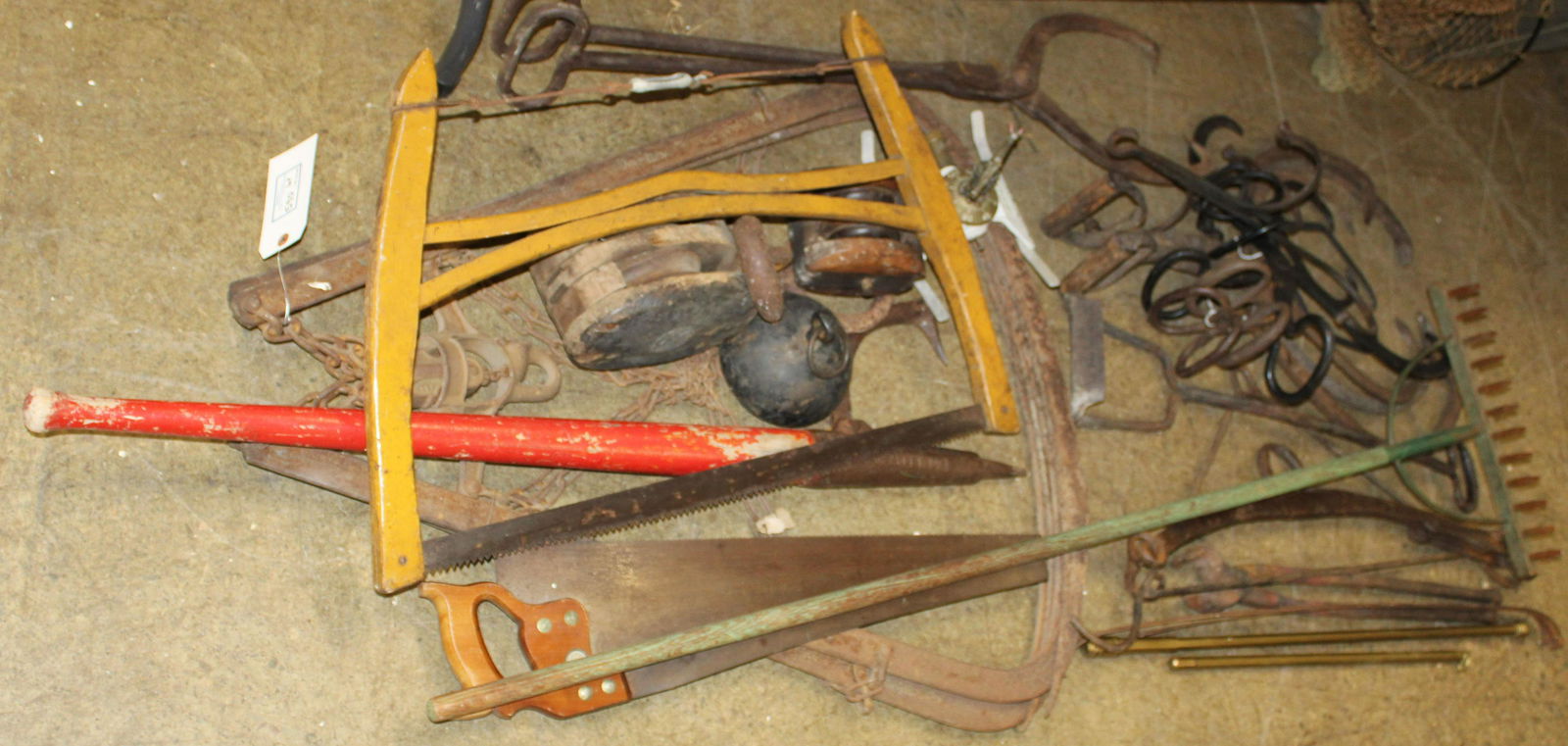 Large Group of Antique Farm Implements: Large group of antique and vintage farm implements including iron hay claws grapple forks, buck saw in old yellow paint, peavey log roll, old wooden rake in green paint, block and tackle, many sets of