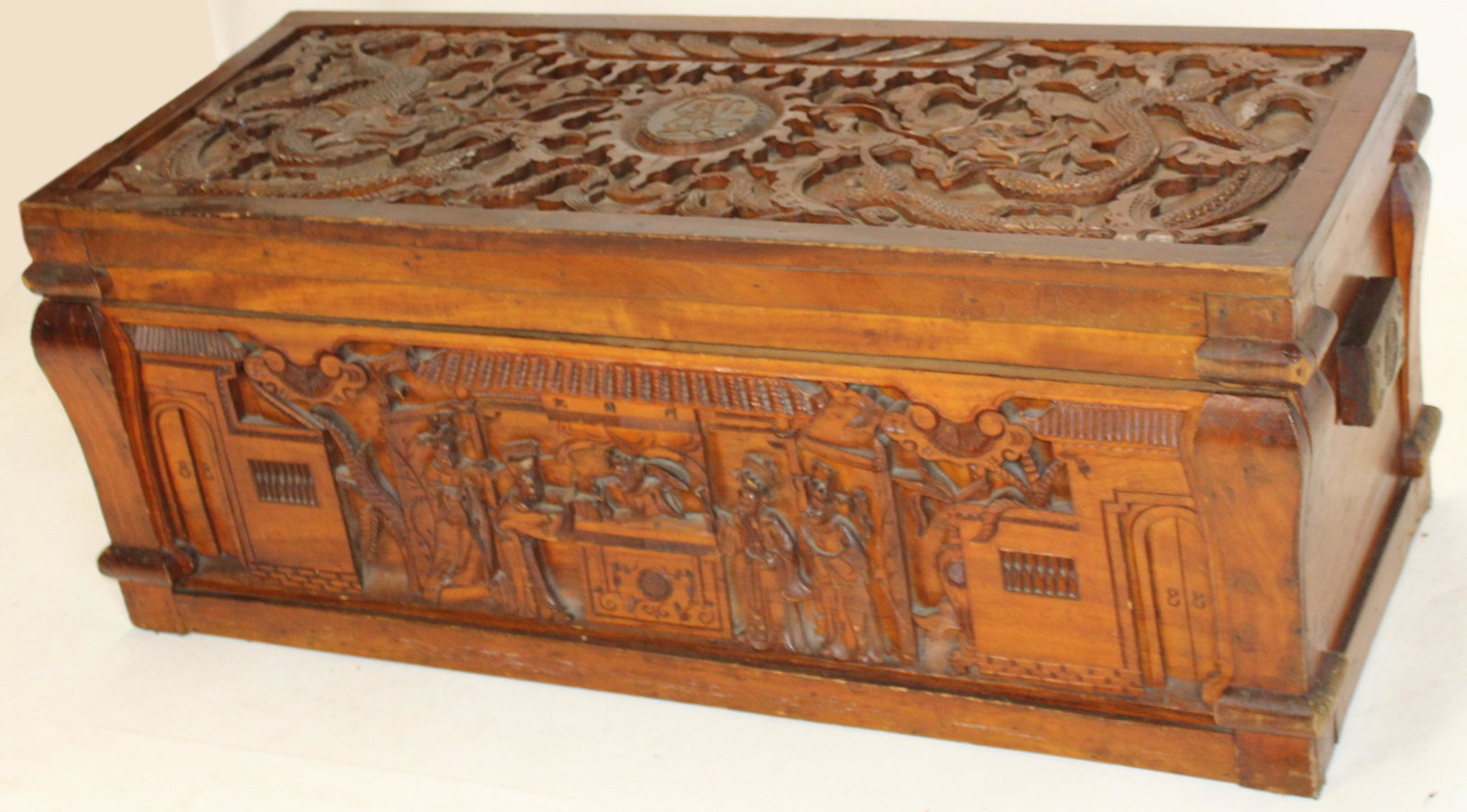 Carved Wooden Chinese Chest: Chinese carved wooden chest, relief design of marketplace on front, top of chest depicts four-clawed dragon. Some breaks in the carvings. 44"x17.5"x17.5"
