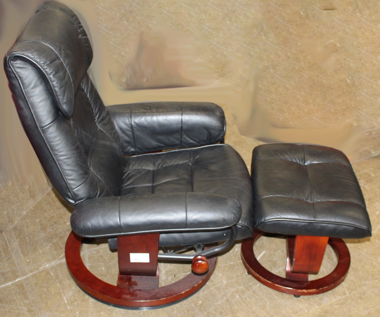Stressless Type Lounge Chair and Ottoman: Contemporary "Benchmaster" black vinyl imitation leather stressless style adjustable reclining lounge chair with ottoman, cherry stained base, in overall good condition 39" x 29" x 25"