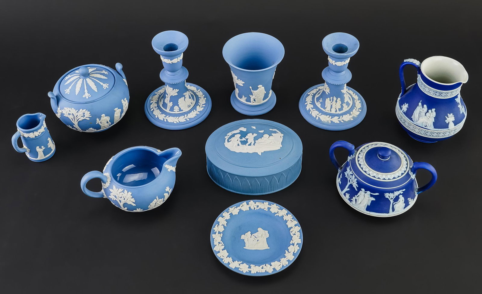 Collection of Wedgwood Blue Jasperware: Collection of 9 pcs. Wedgwood Jasperware pottery tableware including deep blue dipped Etruscan jug and sugar bowl, pair of solid light blue candlesticks, sugar bowl and flared vase, low creamer, minia