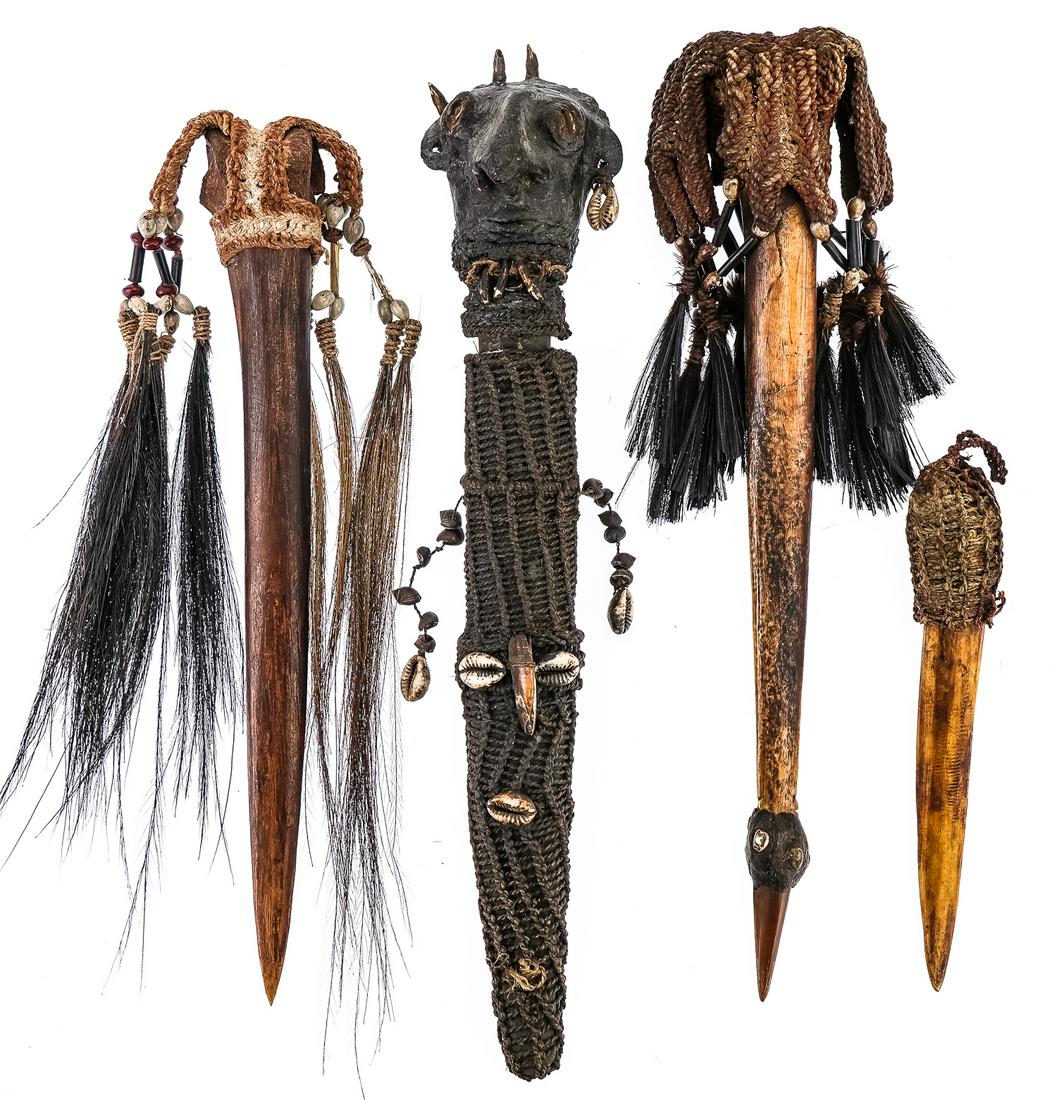 Four Asmat Bone Daggers: Four Asmat Cassowary bone daggers, with braided pommel decorations. One has a sheath and sculpted head pommel with ear piercing, horns. 7.5"-14"